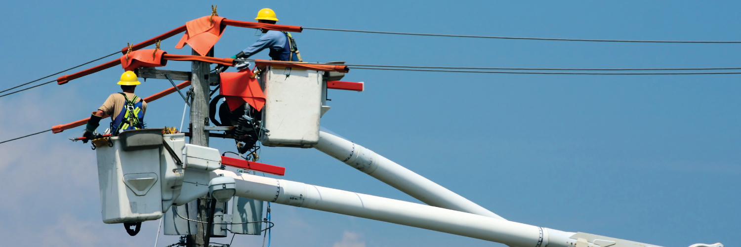 Three lineworkers in bucket trucks doing repair work on a utility pole