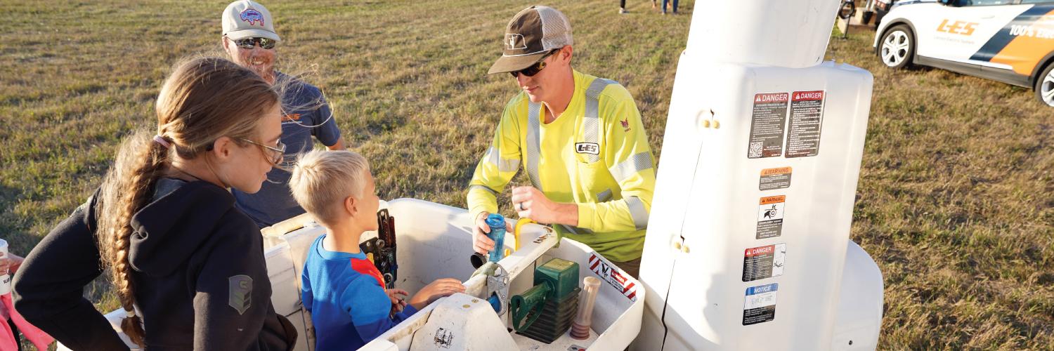 A Lincoln Electric System crew member assists kids in a bucket truck during a community event