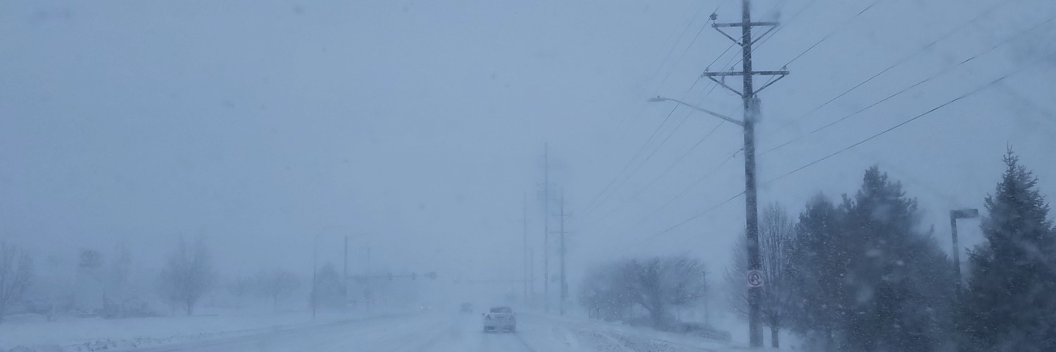 Highway with blizzard conditions - blowing snow - and power lines to the the right (screened)