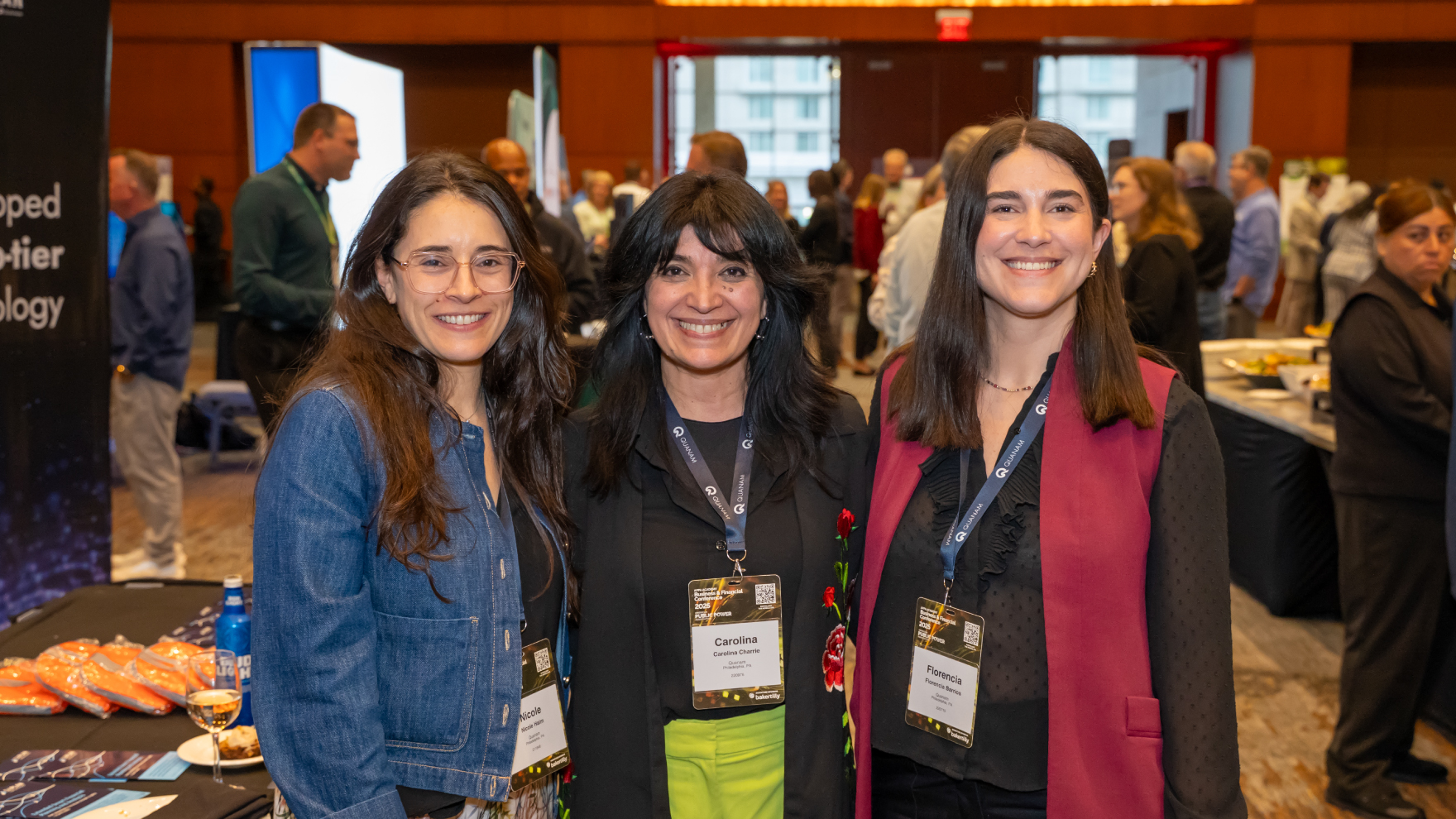 Three people posing for a photo in a conference's sponsor area