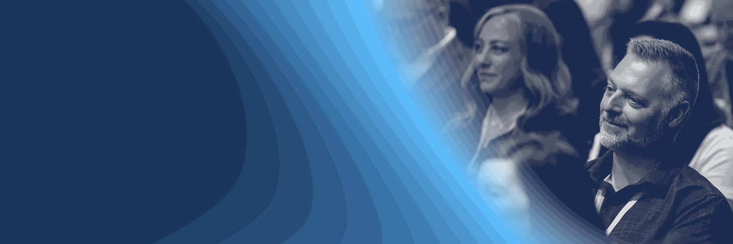 Black-and-white image of people listening to a conference session with a blue graphic overlay