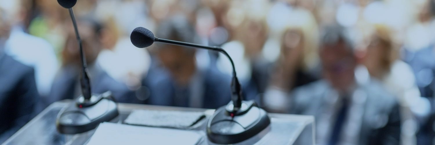 View from a podium with microphones looking out over a crowded room.
