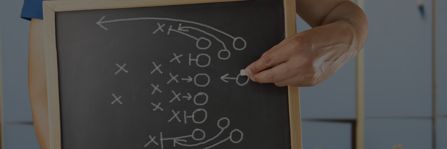 Closeup of chalkboard with X's and O's with hand holding chalk