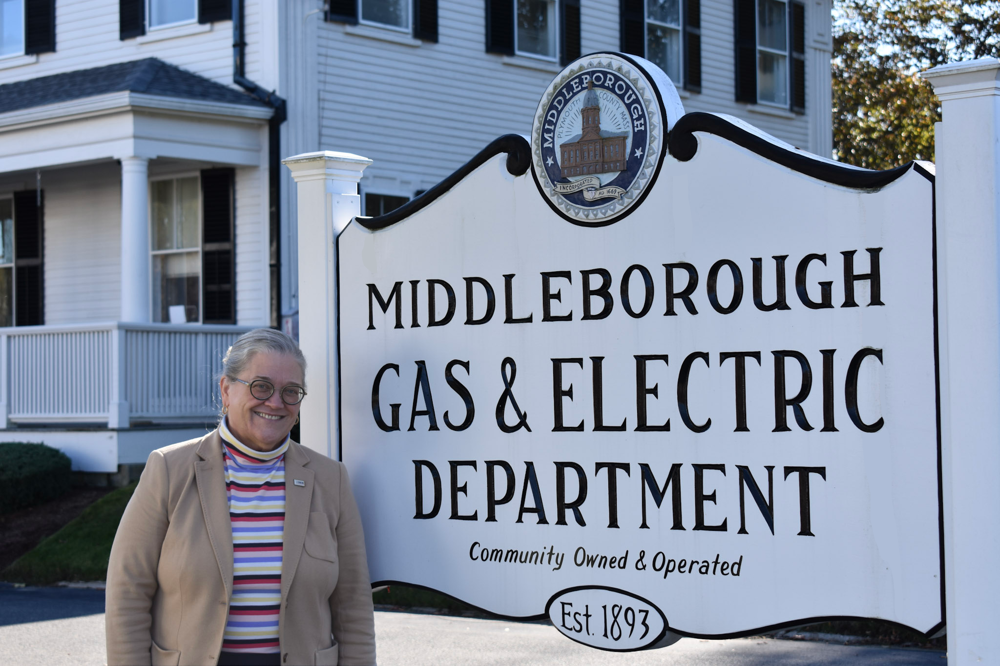 Jackie Crowley next to a sign for Middleborough Gas and Electric