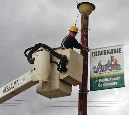 A worker with Clastkanie People's Utility District in Oregon hangs a street sign