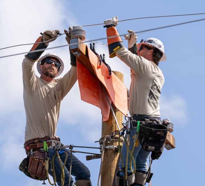 Two lineworkers atop a power pole