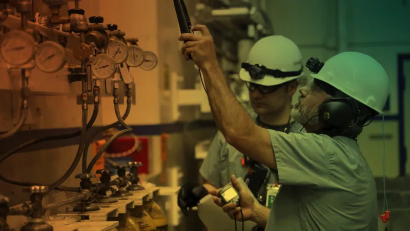 Two people in hardhats examining large machinery