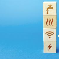 Wooden cutouts depicting a community next to a stack of wood blocks with utility icons