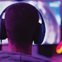 teen wearing headphones sitting at a computer
