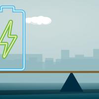 Battery and person on opposite ends of a scale in front of a city skyline