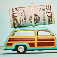 Retro wood paneled station wagon toy with roll of US currency tied on top