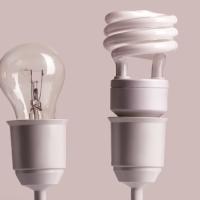 a candle and three types of light bulbs in a line, showing how light sources have evolved