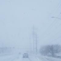 Highway with blowing snow and blizzard conditions with power lines on the right
