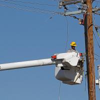 A lineworker in a bucket truck working on top of a utility pole