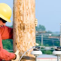 A lineworker climbing on top of a utility pole