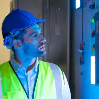 man in yellow vest looking at a glowing item