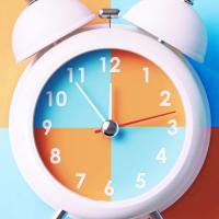 Orange and blue alarm clock on checkered background