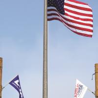 US flag above lineworkers holding utility and state flags at the 2024 Public Power Lineworkers Rodeo