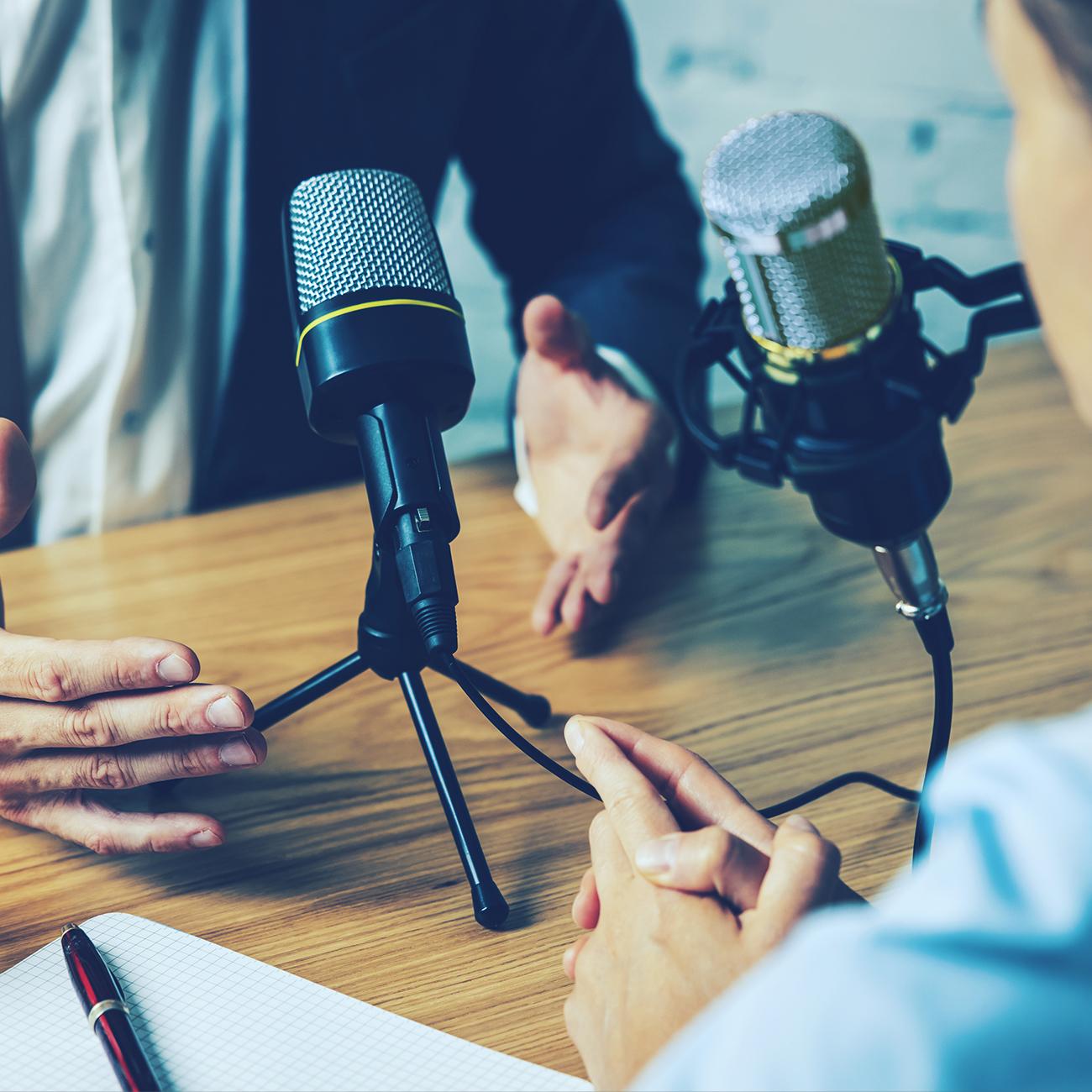 two people across a table talking into microphones