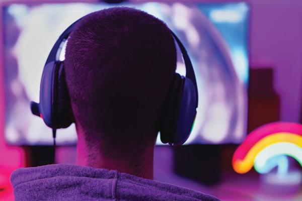 teen wearing headphones sitting at a computer