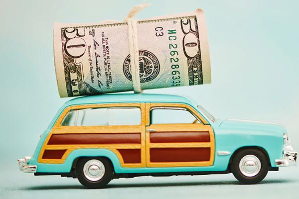 Retro wood paneled station wagon toy with roll of US currency tied on top
