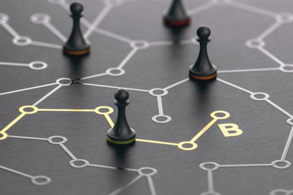 Black chess pawns on a board with a network pattern and a line highlighted in gold