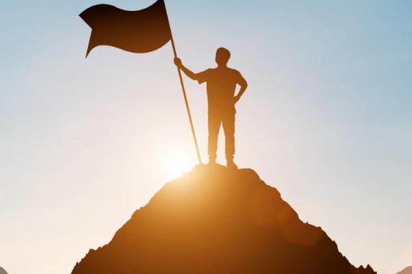 A silhouetted figure holding a flag atop a hill