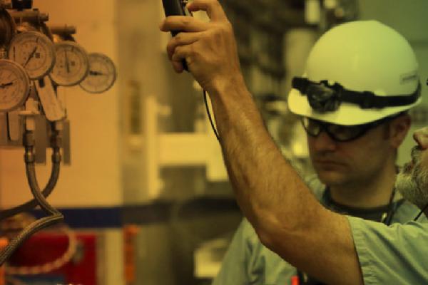 People in hardhats examining machinery