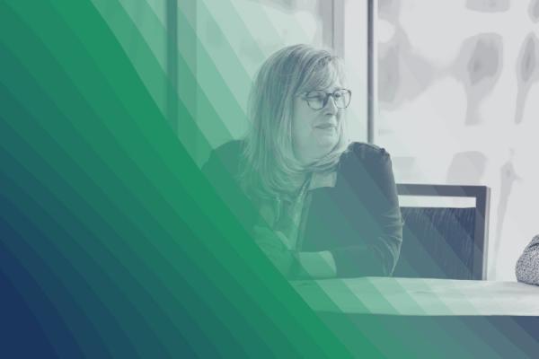 Black-and-white photo of two people talking with a green-hued curve graphic