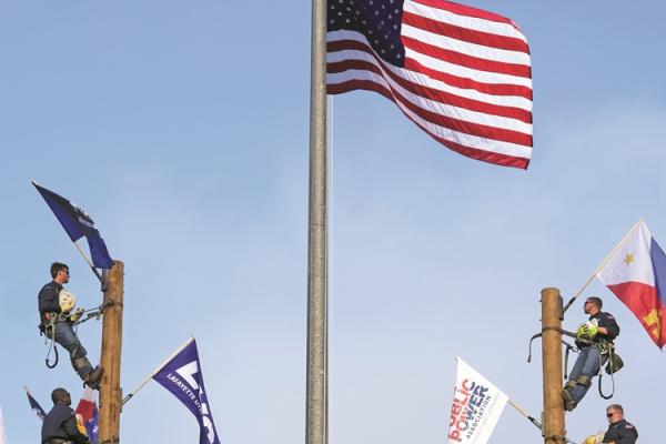 US flag above lineworkers holding utility and state flags at the 2024 Public Power Lineworkers Rodeo
