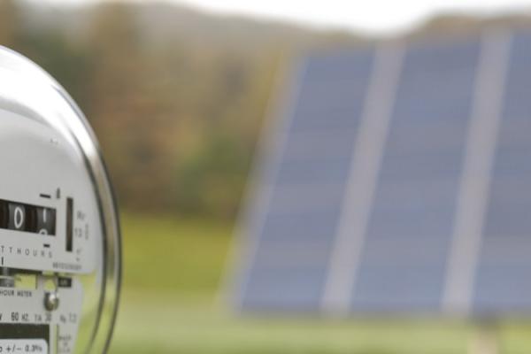 Electric meter with solar panel in the background.