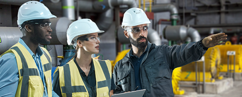 Three people in hardhats in a power plant
