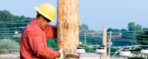 A lineworker climbing on top of a utility pole