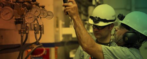 People in hardhats examining machinery