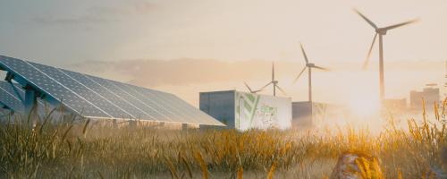 Wind turbines and solar panels in a sunlit field, with a cityscape silhouetted in the background.