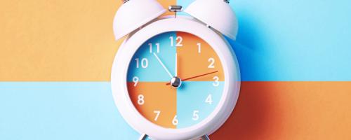 Orange and blue alarm clock on checkered background