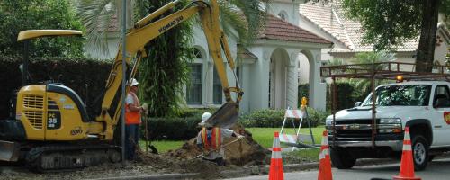 A crew does undergrounding work in front of residences in Winter Park, Florida