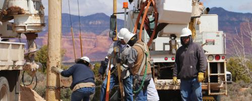 Utility workers install electric poles and lines in the desert on the Navajo Nation
