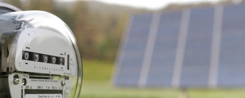 Electric meter with solar panel in the background.