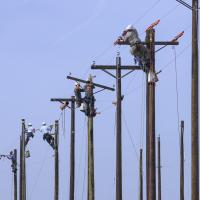 Utility lineworkers atop power poles.