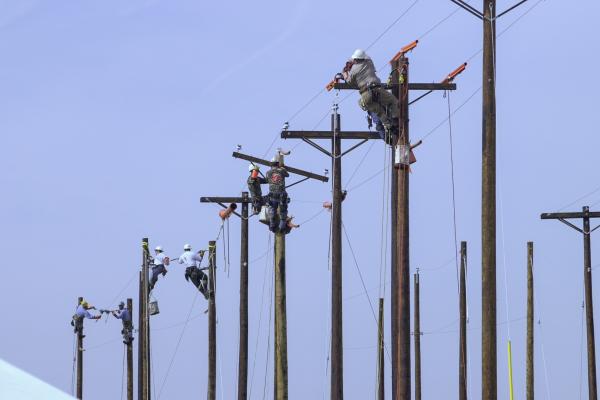 Utility lineworkers atop power poles.